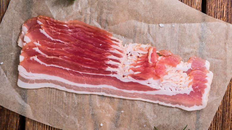 Raw slices of bacon on parchment paper