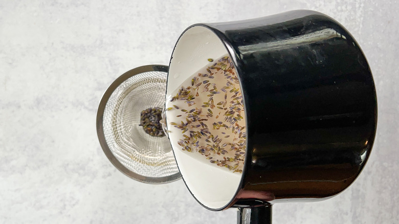 Straining lavender simple syrup from saucepan into jar