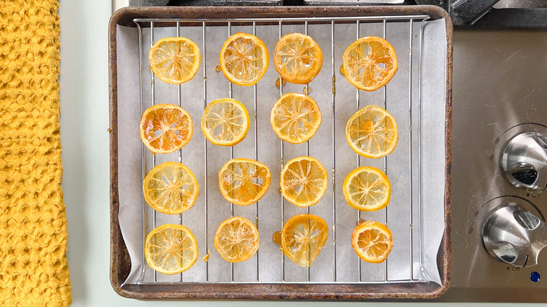Candied lemon wheels on a rack over parchment on baking sheet
