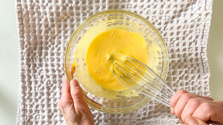 Egg yolks and sugar whisked together in bowl 