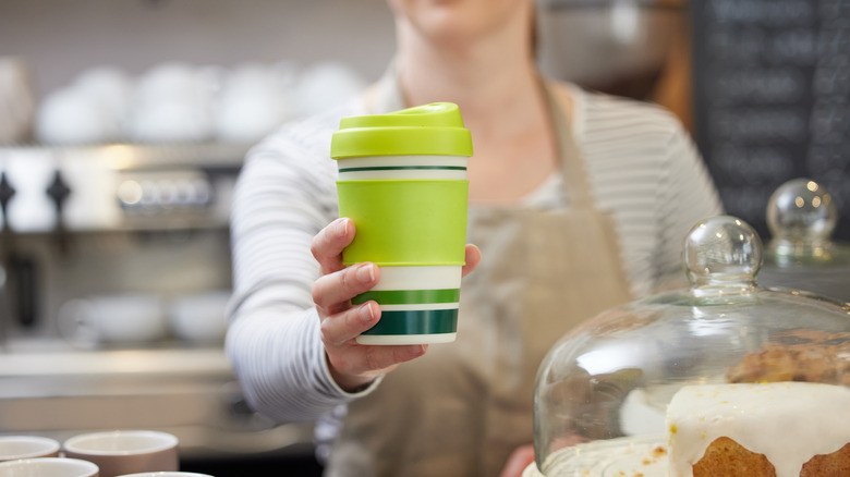 barista handing reusable cup