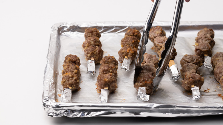 turning cooked meatballs on skewers