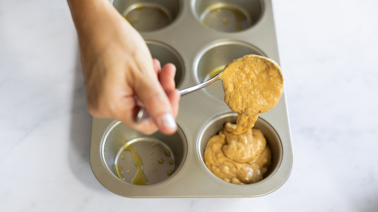 spooning muffin batter into pan