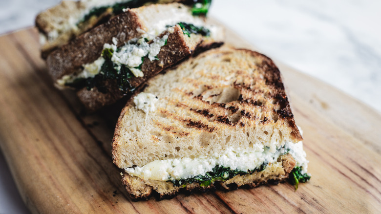 Two halves of grilled cheese on wooden cutting board