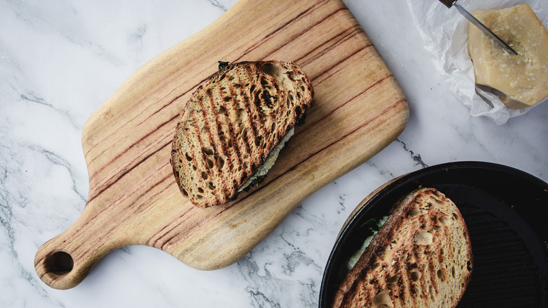 Grilled cheese on cutting board with second in pan