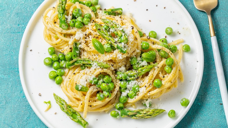 Overview of green peas and asparagus over plain spaghetti