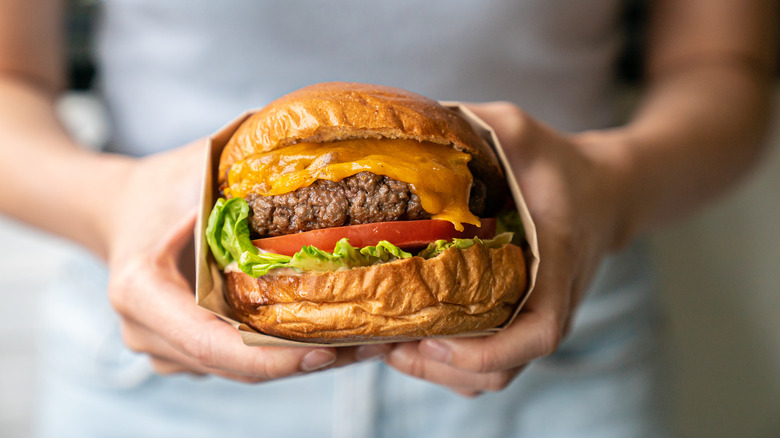 hands holding a cheeseburger