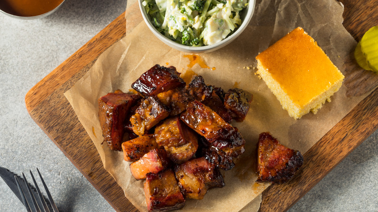 burnt ends on a wood board with cornbread