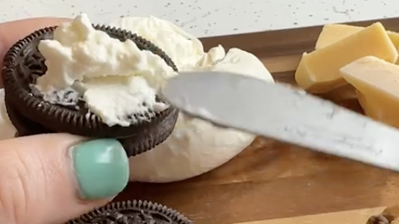 spreading burrata on Oreo