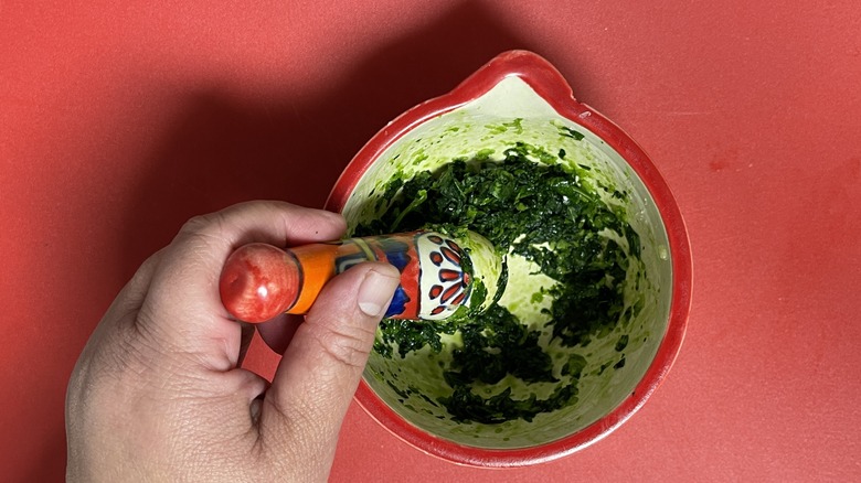 hand mashing parsley in mortar