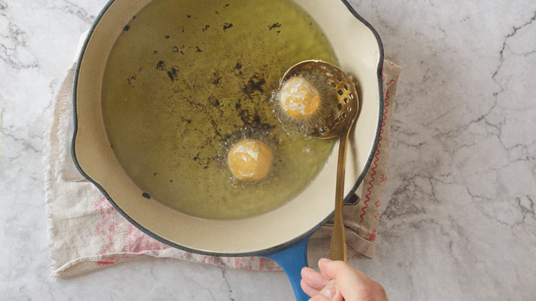 Hand ladling kofta into hot oil