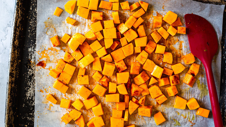 cubed seasoned squash on baking sheet with spatula