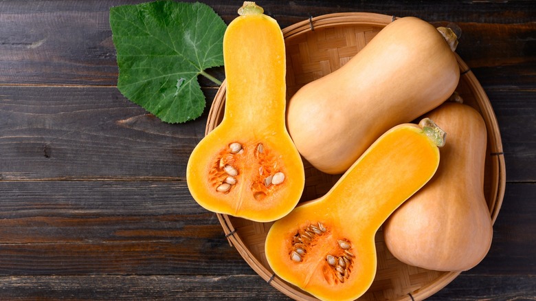 Top-down view of whole and halved butternut squash in a bowl