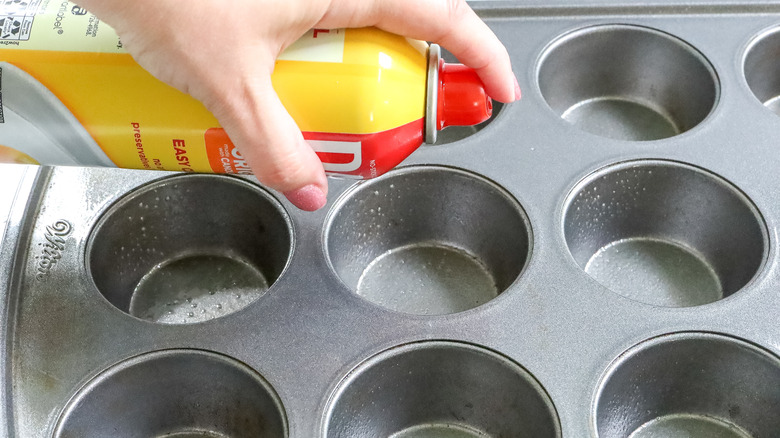 spraying muffin tin with oil