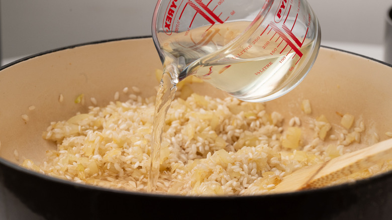 pouring wine into risotto