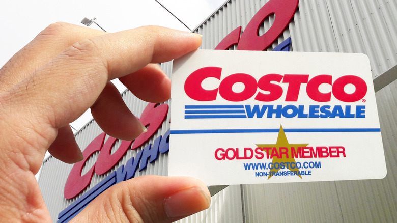 Hand holding up a Costco membership card outside the store