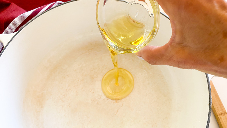 hand adding oil to pot