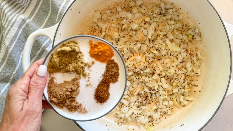 hand adding spices to pot