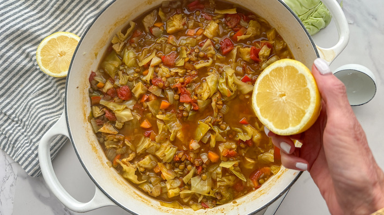 hand adding lemon to soup