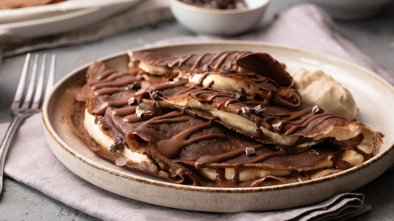 plate of chocolate crepes with chocolate sauce and whipped cream