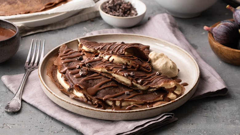 plate of chocolate crepes with chocolate sauce and whipped cream