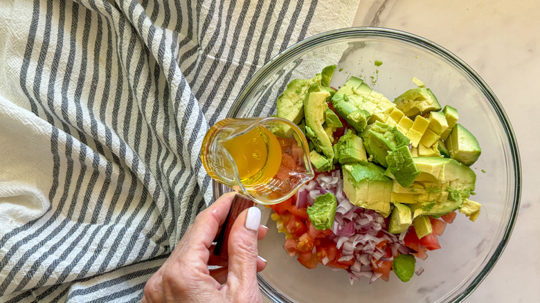 hand adding oil to  bowl