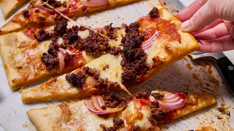 hand taking slice of flatbread from table