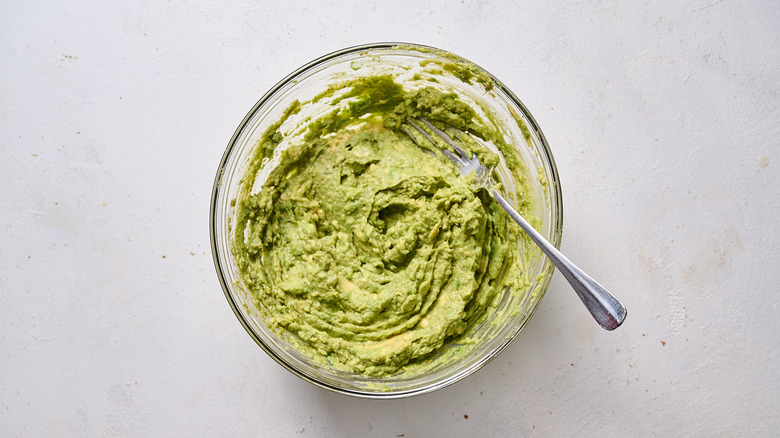 mashing avocado in bowl