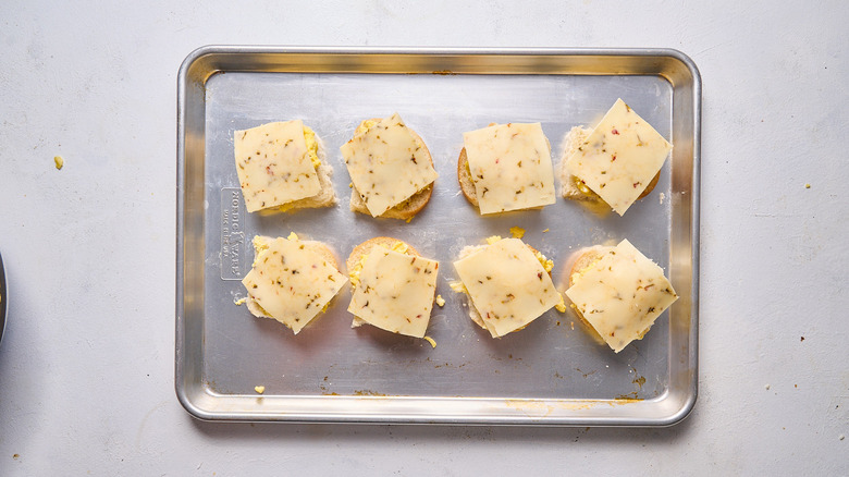 egg and cheese breakfast sandwiches in assembly on sheet tray