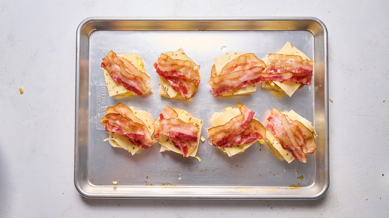 egg and bacon breakfast sandwiches in assembly on sheet tray