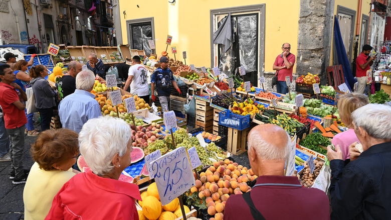 People surrounding fruit stands in Naples food market