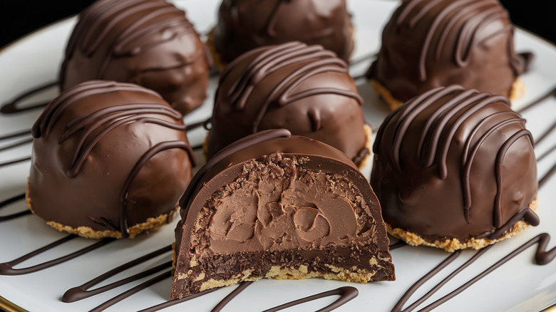 chocolate truffles on a white plate with chocolate drizzling with one truffle in the foreground cut in half to show the insides