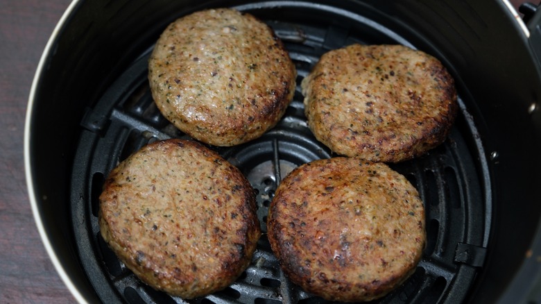 Four burger patties in an air fryer