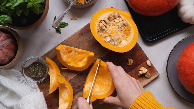 Hands slicing up a pumpkin