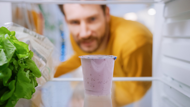 Man looking at yogurt in fridge 