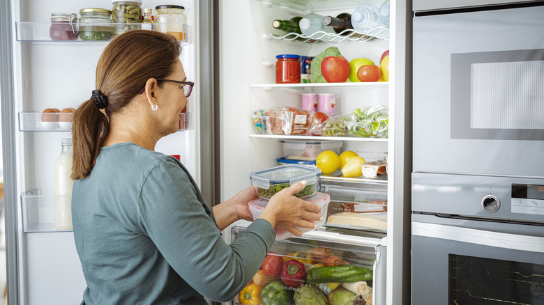 woman places food into fridge