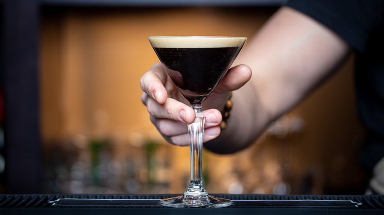 Hand placing espresso martini on bar