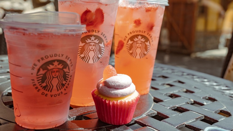 Three Starbucks Strawberry Lemonade Refreshers with a cupcake