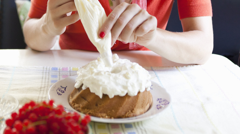 putting frosting on a baked cake