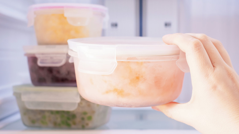 person taking out container of frozen leftovers from freezer