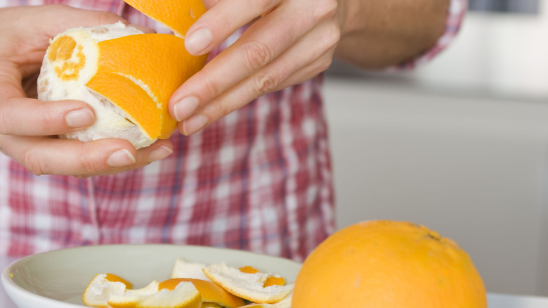 Hands peeling orange