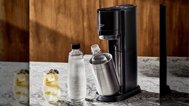 Sodastream machine and accessories with glass of sparkling water