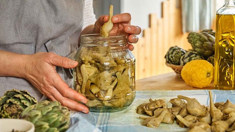 hand taking out canned artichoke