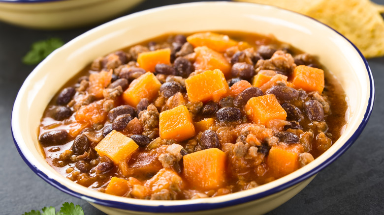 A bowl of stew filled with beans, pumpkin, and ground beef