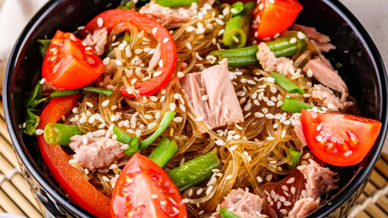 Closeup of a bowl of stir-fried tuna, vegetables, and glass noodles