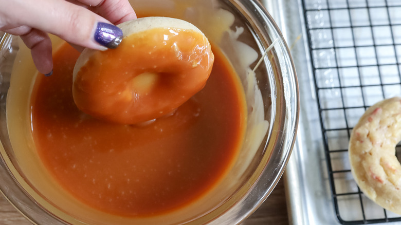 dipping donuts in caramel glaze