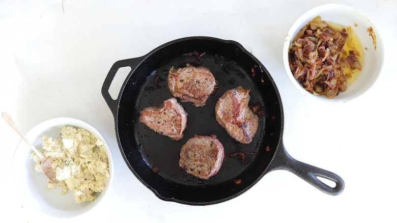 steaks in black frying pan