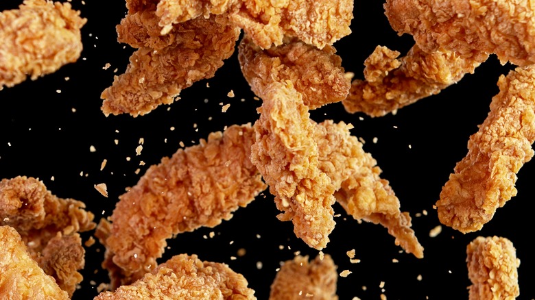 Fried chicken falling black backdrop