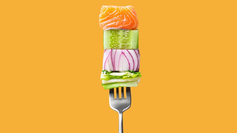 Raw food on fork orange background