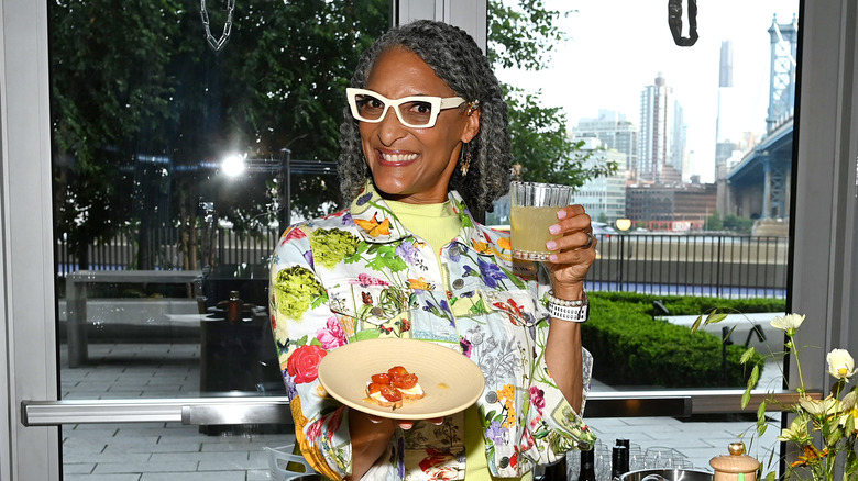 Carla Hall holding glass and plate of food